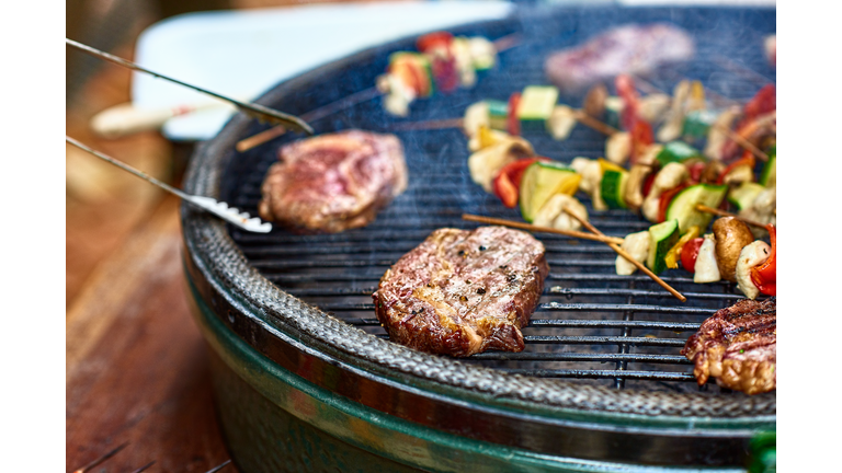 Succulent steak cooking on bbq grill with vegetables