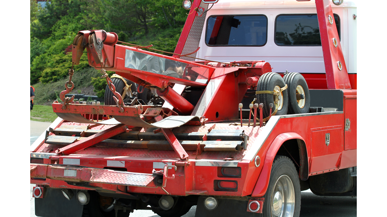 Close-up of red tow truck in a road near trees