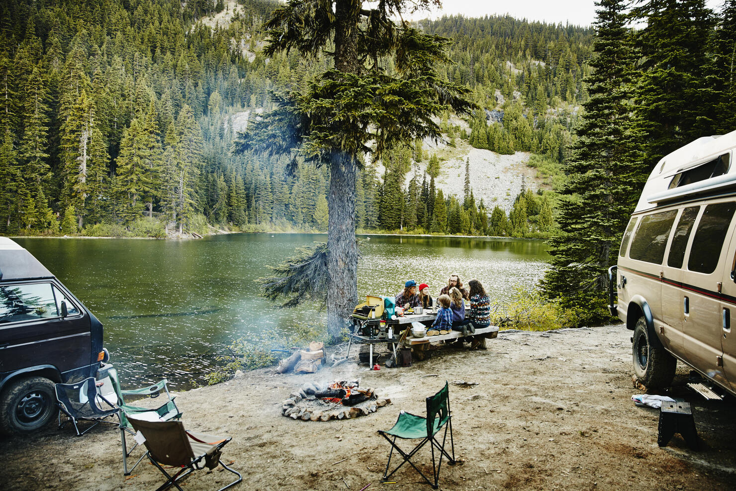 Friends sharing a meal while camping by lake