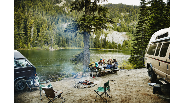 Friends sharing a meal while camping by lake
