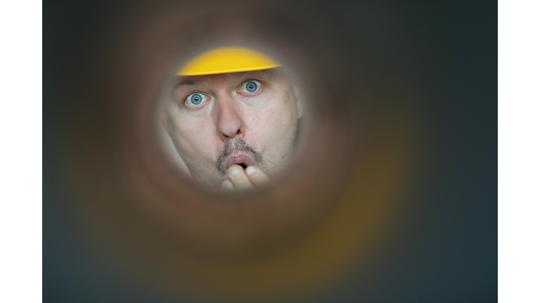 Male plumber looks into contaminated pipe