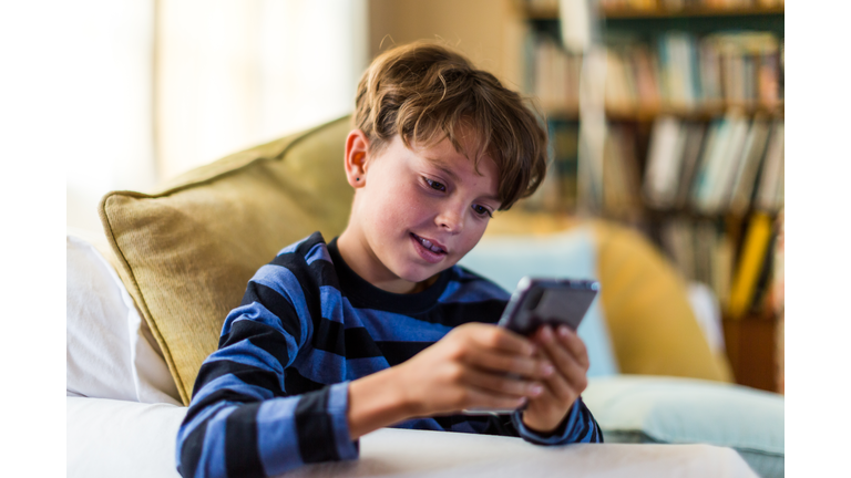 Boy playing alone on smart phone in living room