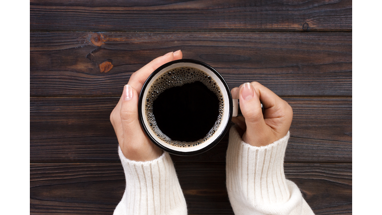 Directly Above Shot Of Woman Hands Holding Black Coffee In Cup On Table