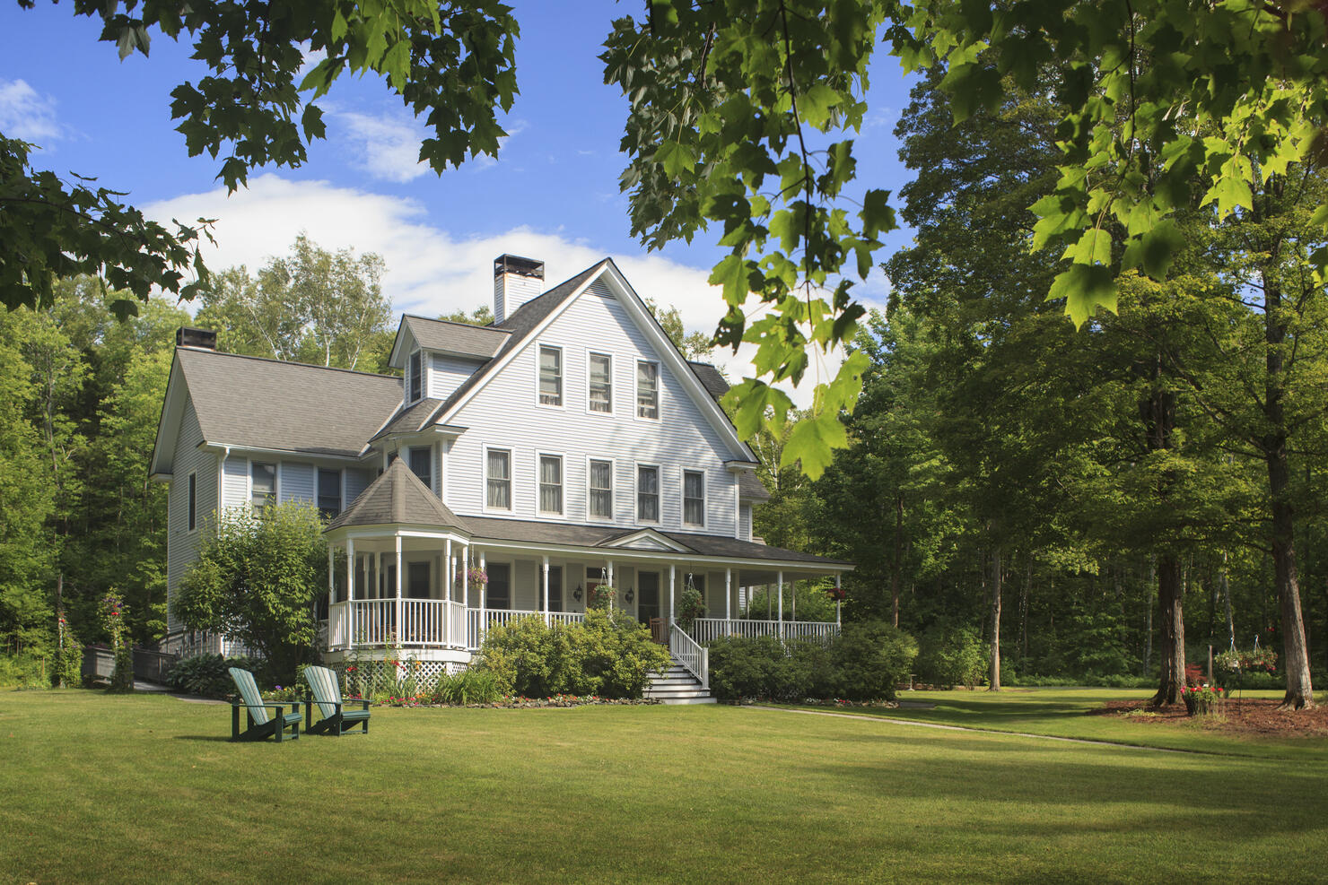 Victorian home with lawn and large front porch in summer