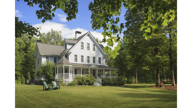 Victorian home with lawn and large front porch in summer