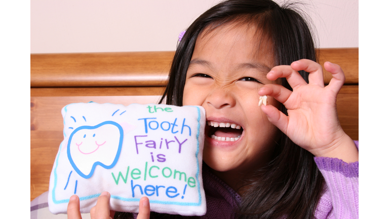 Chinese little girl holding up her tooth