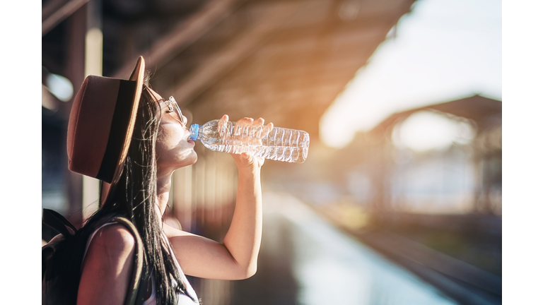 Woman Drinking Water From Bottle At Railroad Station Platform