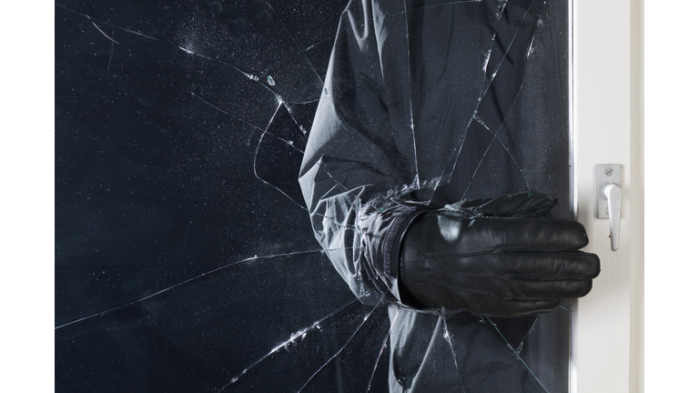 A criminal breaking into a window, focus on hand