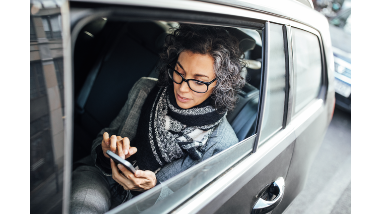 Businesswoman testing while traveling by a car