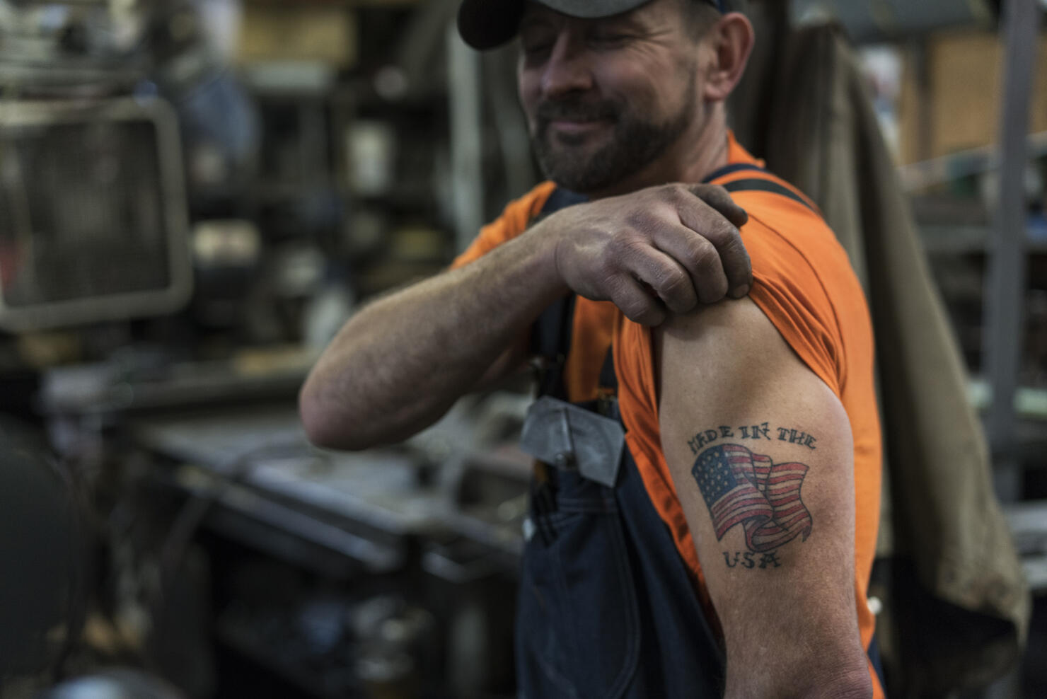 Caucasian worker displaying tattoo in factory