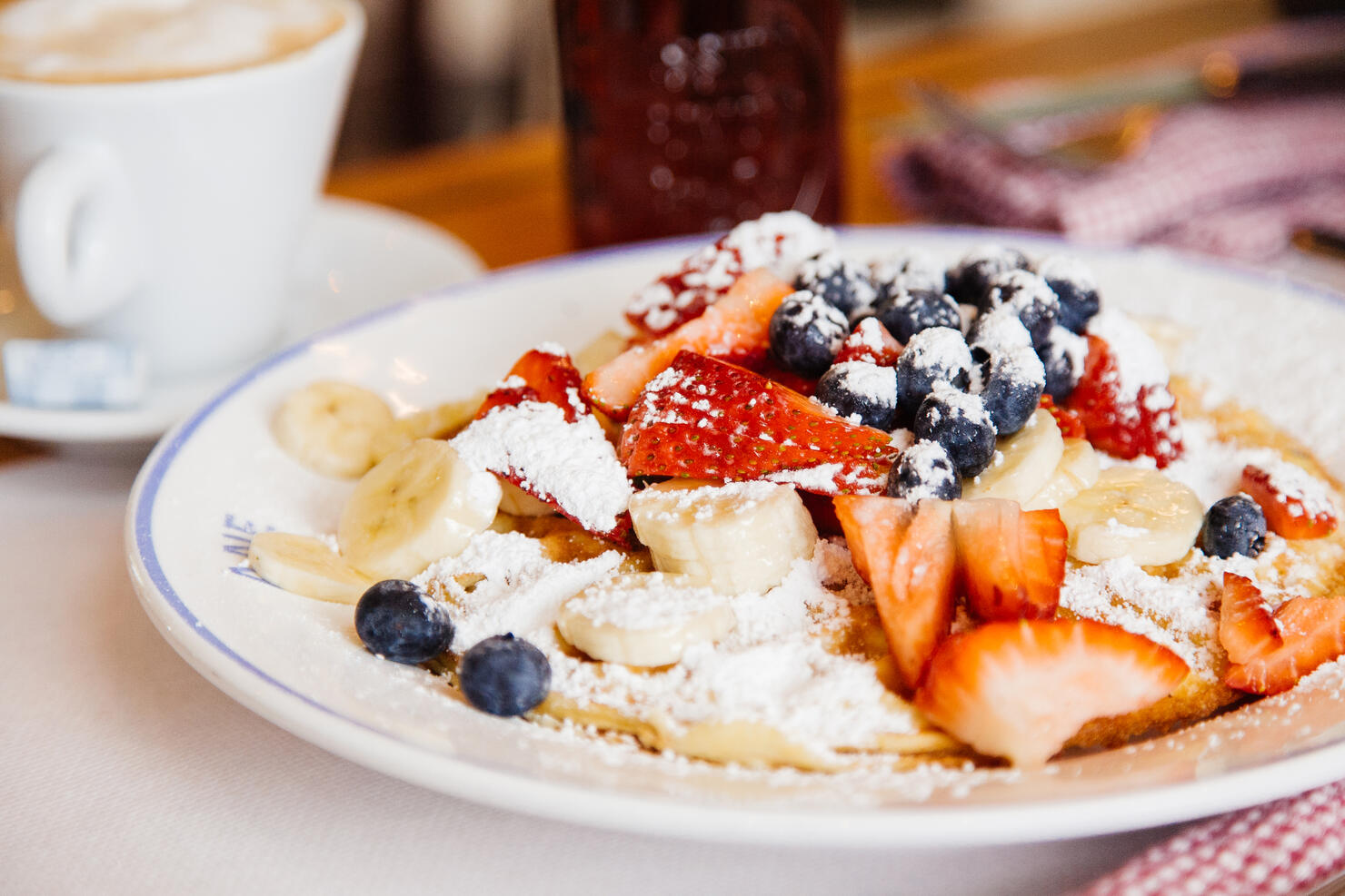 Traditional American breakfast - pancakes with fresh banana, blueberry and strawberry