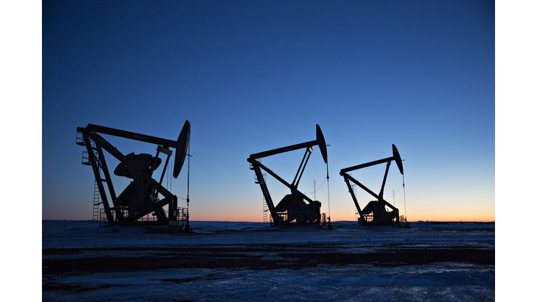 The silhouettes of pumpjacks are seen above oil wells in the Bakken Formation