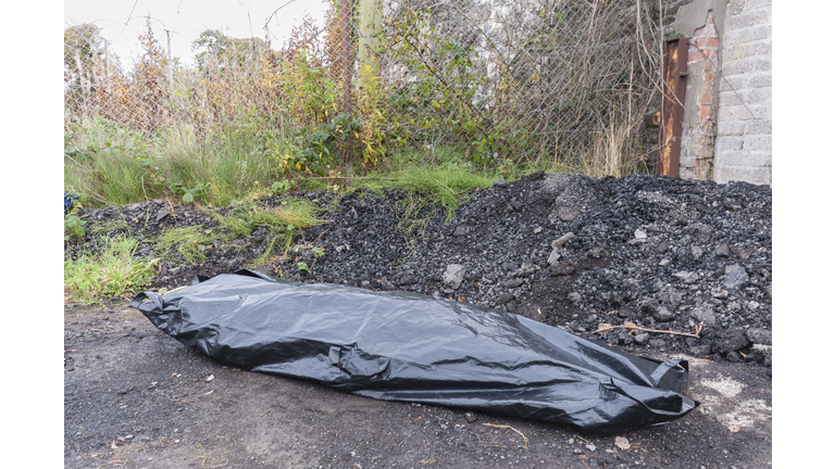A body inside a body bag at an isolated location.
