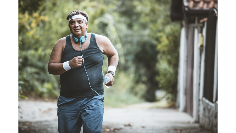Fat man slowly running outdoors, active lifestyle as struggle with obesity