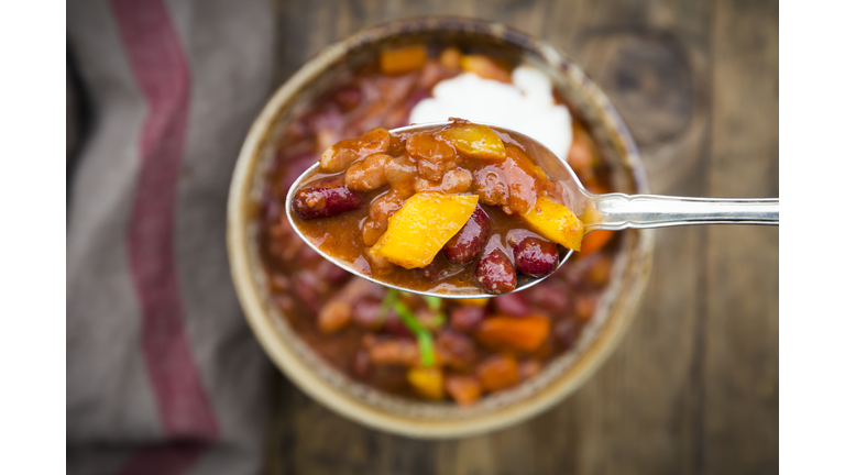 Chili con Carne with coriander and sour cream, spoon, close-up