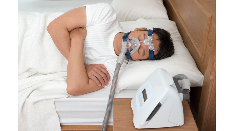 Man Wearing Cpap Mask While Suffering From Sleep Apnea On Bed At Home