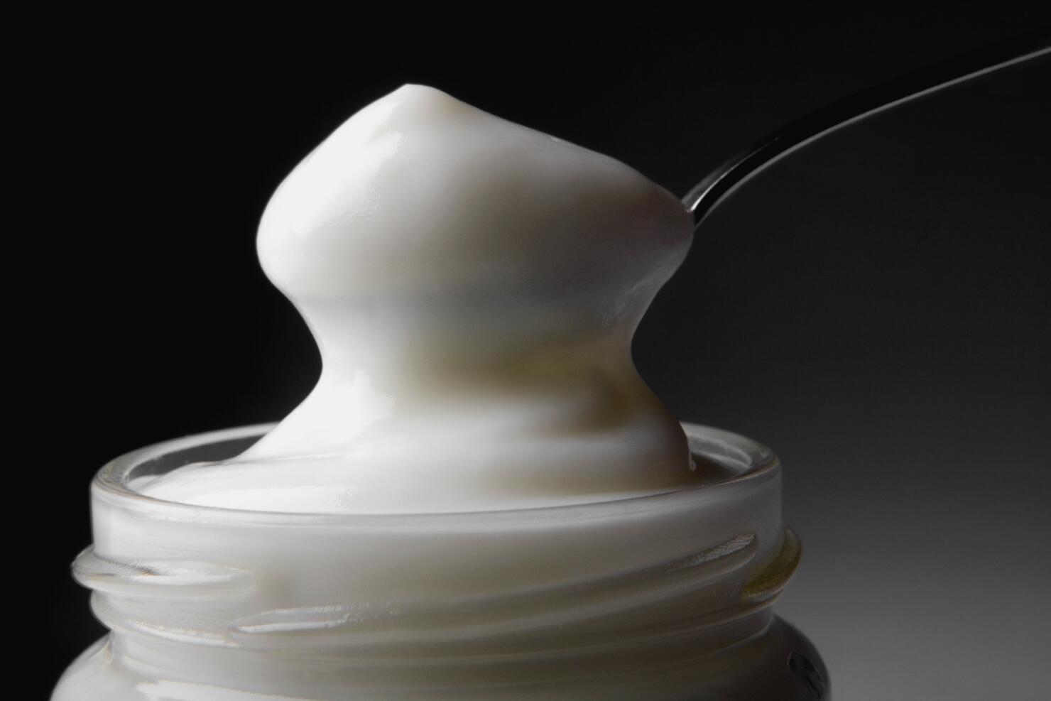 Close-up of a spoon in a jar full of mayonnaise