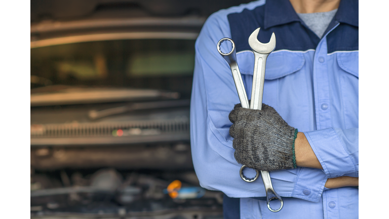 Professional Mechanic in the garage. Auto repair garage. Hands of car mechanic with wrench in garage.