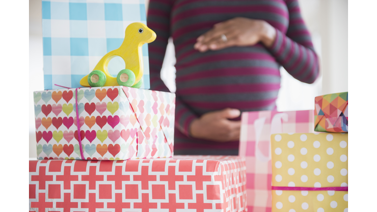 Black pregnant woman admiring gifts at baby shower