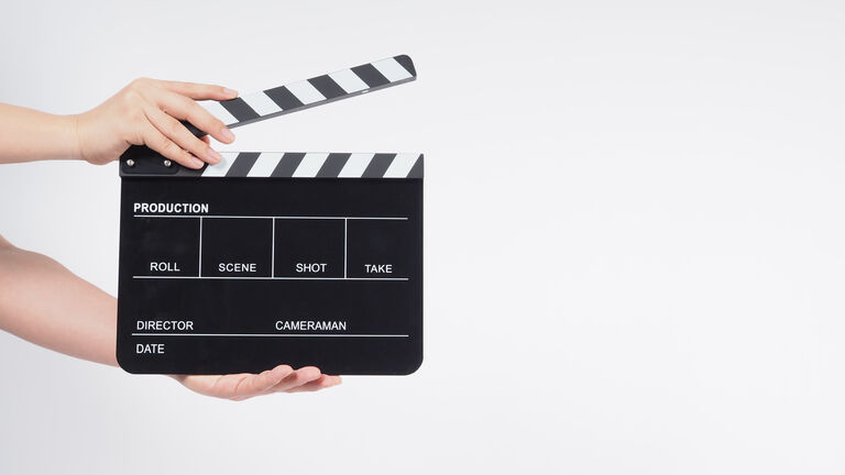 Cropped Hand Of Person Holding Film Slate Over White Background