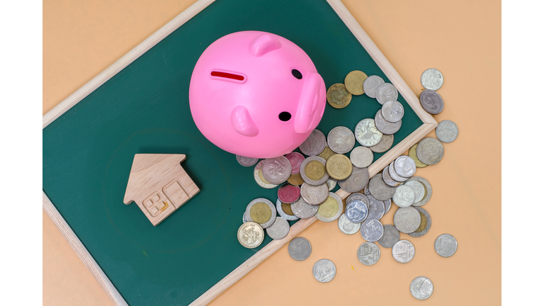 Home savings, budget concept. Model house, piggy bank and money on wooden office table.