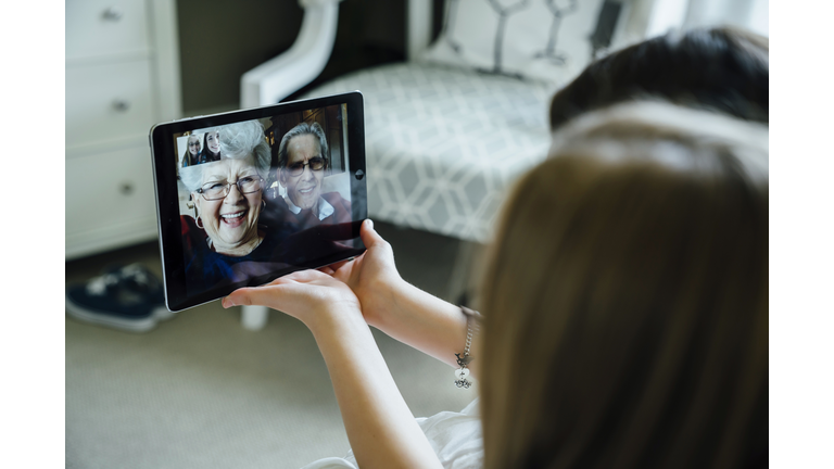 Sisters video conferencing with grandparents through tablet computer at home