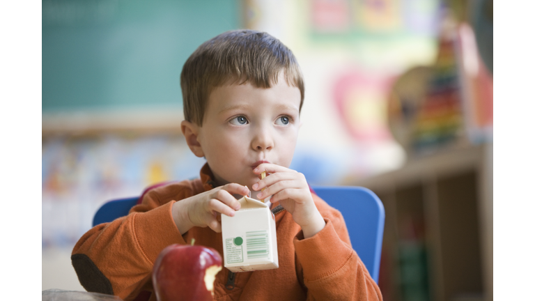 Caucasian boy eating lunch in classroom