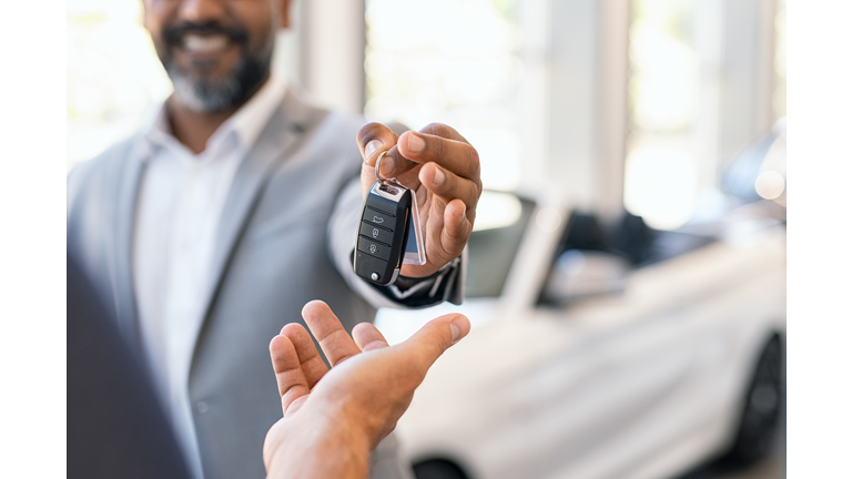 Salesman giving new car keys to customer