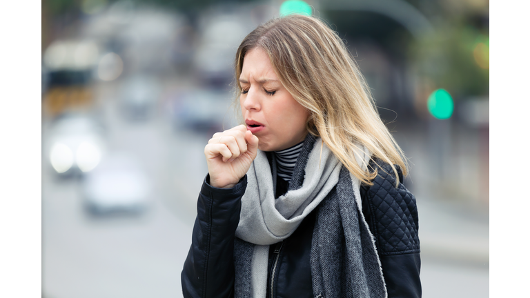 Illness young woman coughing in the street.