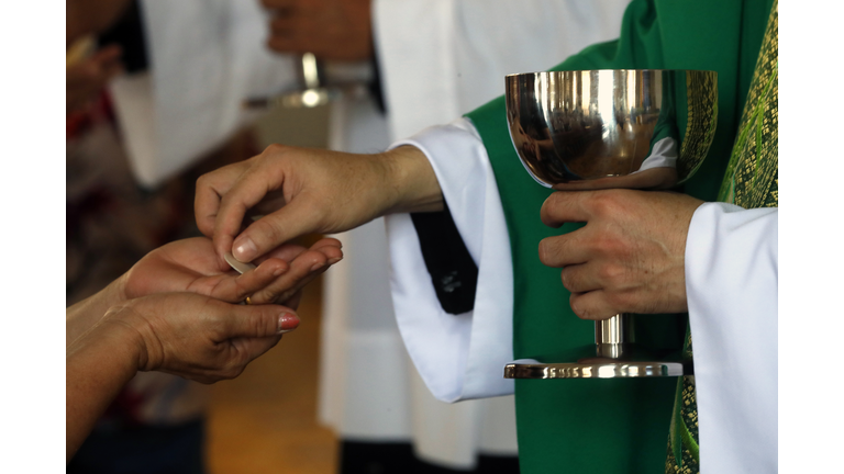 Catholic mass. Priest giving the Holy Communion.  Chau Doc church. Vietnam.