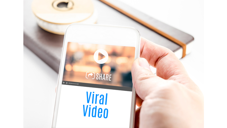 Close up hand holding smart phone with Viral Video word