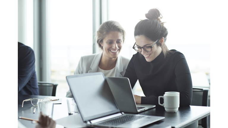 Co-workers having meeting with laptop in conference room