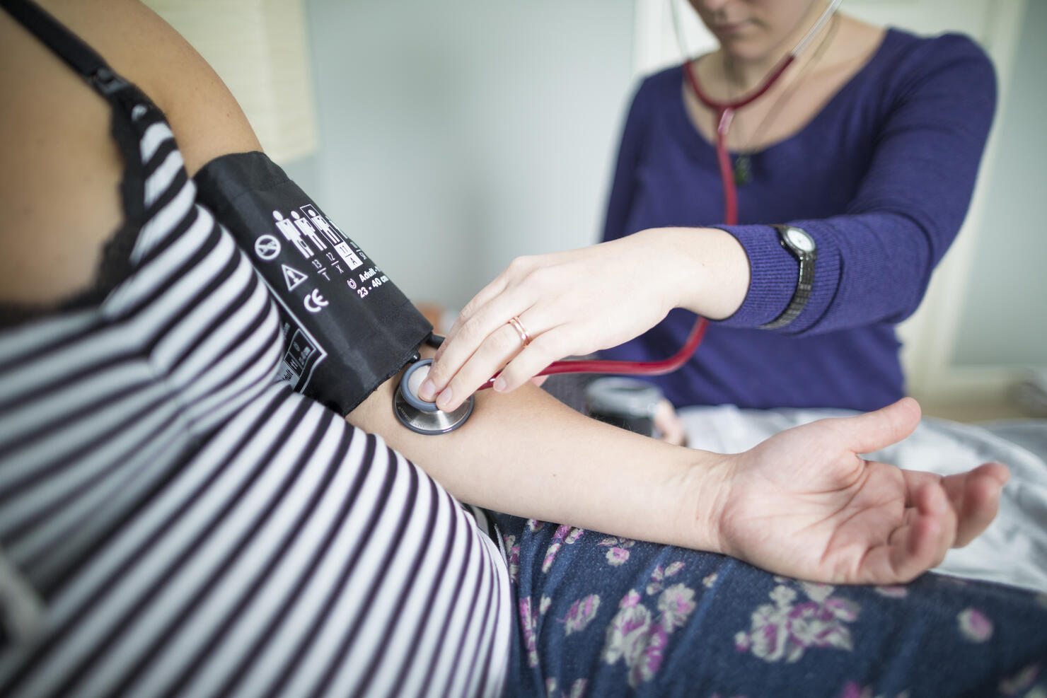 Midsection of midwife examining pregnant woman at home
