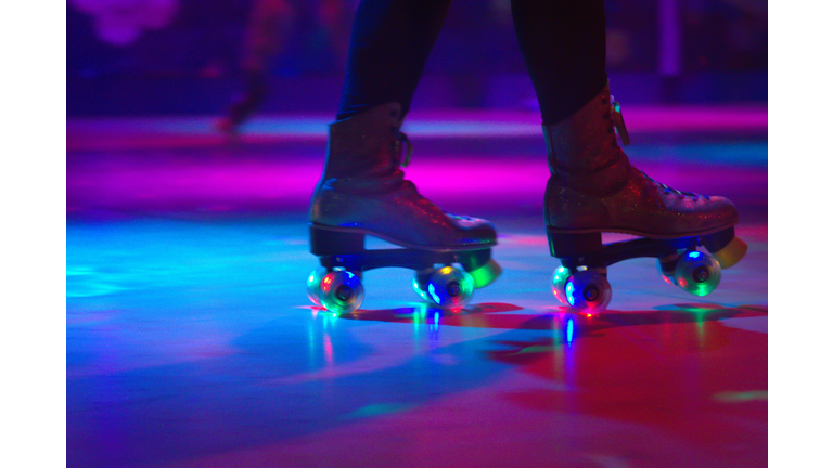 Low Section Of Person Roller Skating On Floor In Illuminated Rink