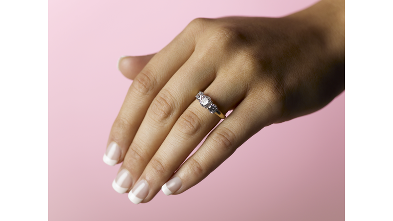Young woman wearing engagement ring, close up of hand (focus on ring)