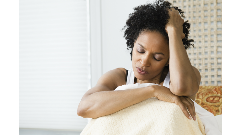 Mid adult woman sitting on the bed and suffering from a headache