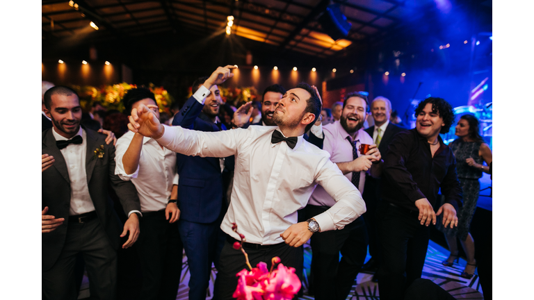 Groom and wedding guests laughing during party