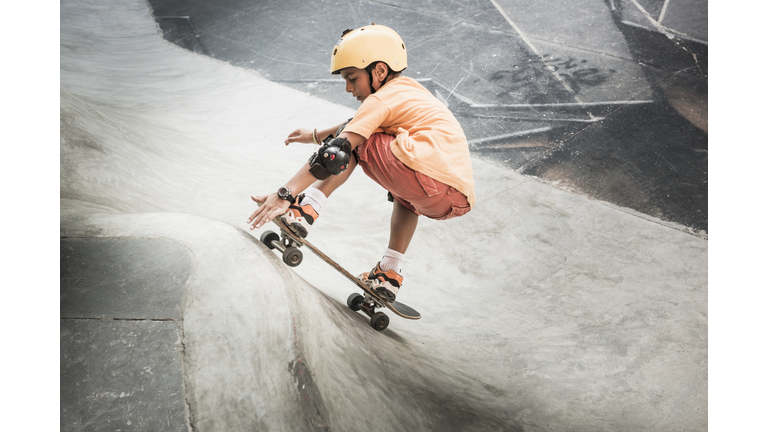 Mixed race boy riding skateboard in skate park