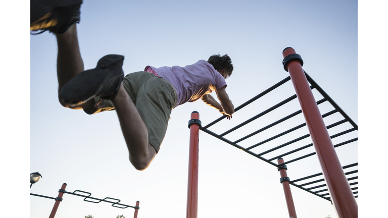 Guy training in park on monkey bars