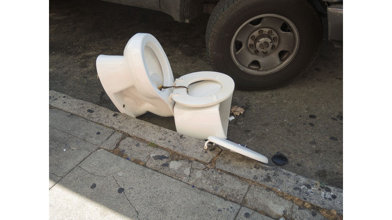 Broken Toilet Laying in the Street with Car Tires