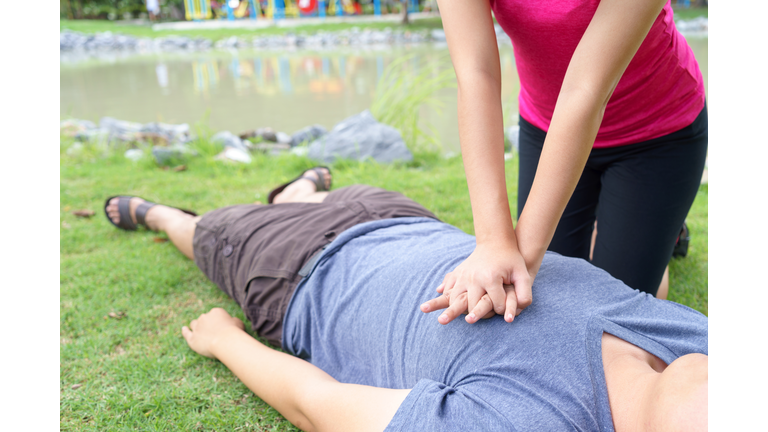 Midsection Of Woman Giving Cpr To Unconscious Victim Lying On Field