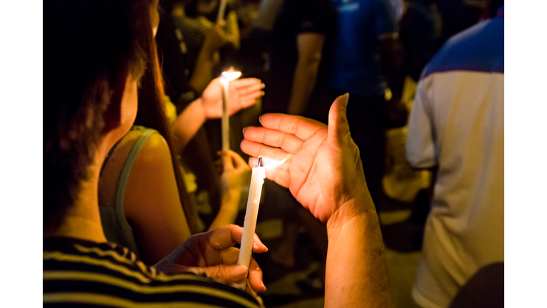 People holding candle vigil in darkness seeking hope, worship, prayer