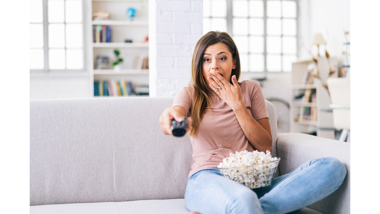 A frightened woman watching tv at home