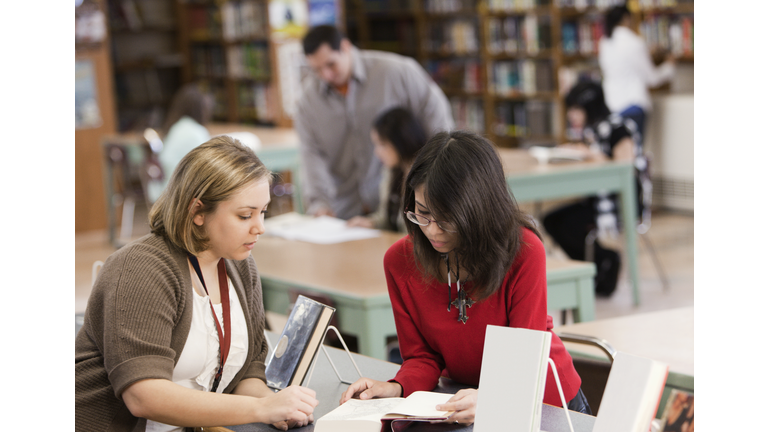Student talking to librarian in school library