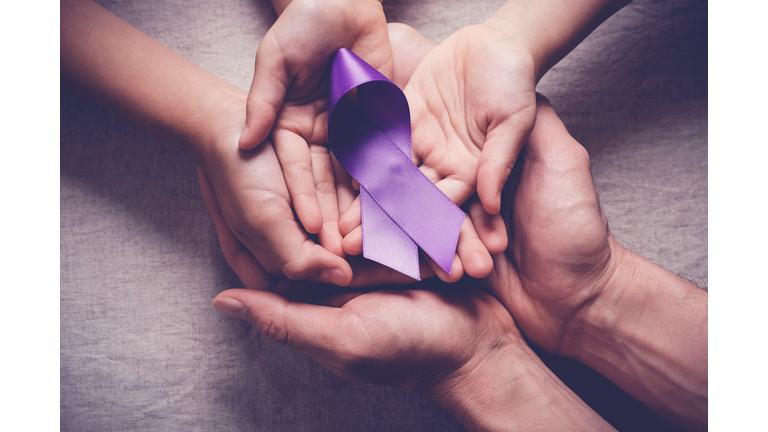 Adult and child hands holding purple ribbons, Alzheimer's disease, Pancreatic cancer, Epilepsy awareness, world cancer day