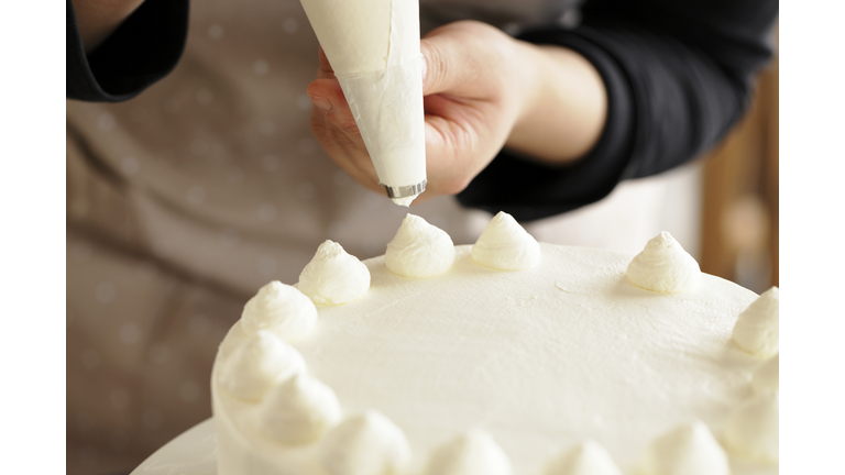 Woman decorating whipped cream on cake