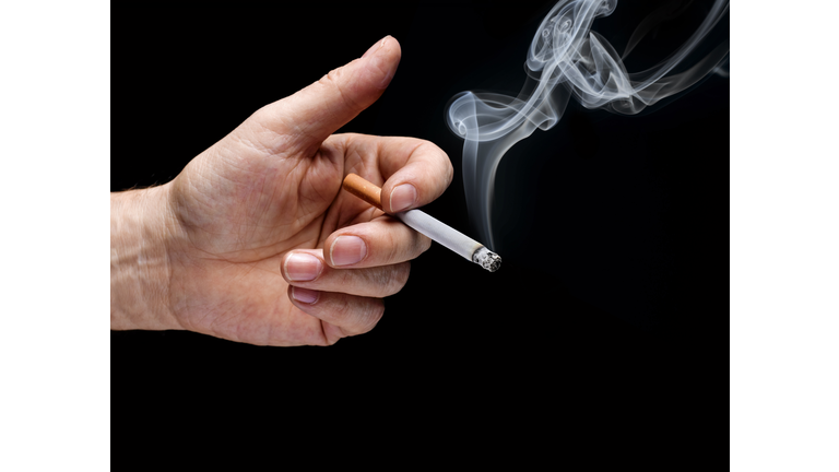 Man's hand holding smoking cigarette