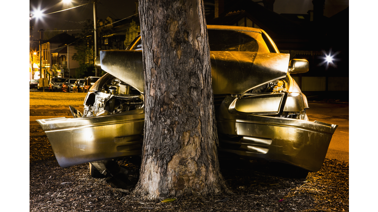 Car crashed on tree trunk at night