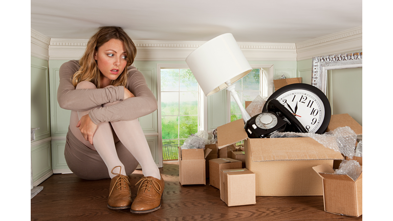 Young woman with box of objects in small room