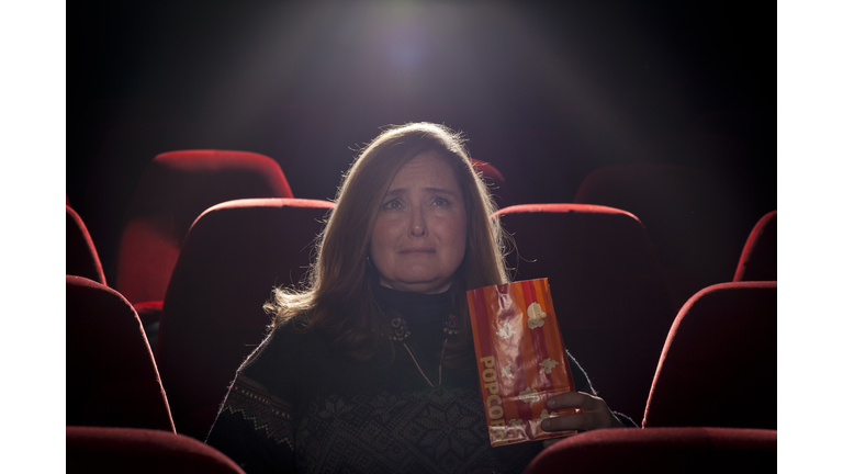 Woman in a movie theater watching a sad movie